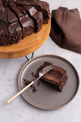 Chocolate cake with a cut piece on gray background, closeup