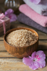 Sea salt, natural handmade soap, natural cosmetic oil and colorful towels with azalea flowers on rustic wooden background