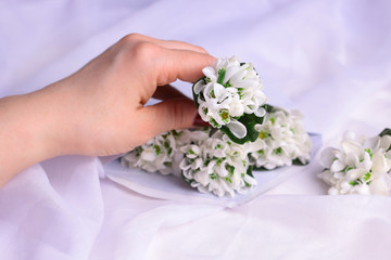 Obraz na płótnie Canvas Young woman hand and white wildflowers in envelope on white fabric background. Romantic communication background concept for mother day, woman day, wedding day and 8 march.. mock up