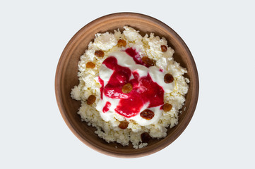 Earthenware plate with cottage cheese and sultana flavored with sour cream and fresh honey. Top view isolated on a white background