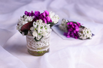 Spring flowers background. Spring purple and white wildflowers on white fabric background.