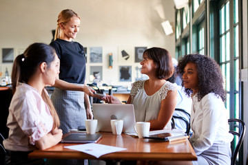 Fototapeta premium Businesswomen Paying Bill At Meeting Around Table In Coffee Shop
