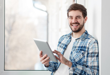 Laughing guy with tablet smiling at camera 