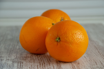 Three oranges on white wooden background