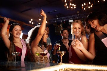 Group Of Dancing Female Friends Celebrating With Bride On Hen Party In Bar