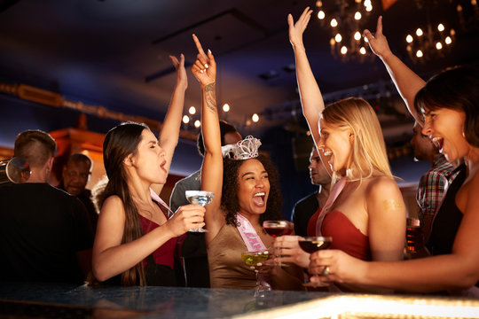 Group Of Dancing Female Friends Celebrating With Bride On Hen Party In Bar