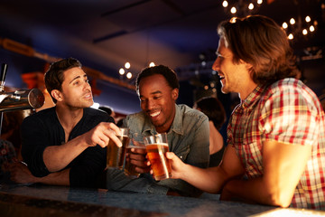 Group Of Male Friends Drinking Beer In Bar Together