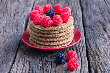 Delicious dutch waffles with caramel and berries on a dark wooden background