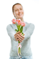 Young beautiful woman gives pink tulips on white background.