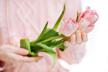 Fototapeta na wymiar Young woman holding pink tulips on a white background.