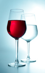 Two glasses. One with wine and the other with water. White turquoise tone. Close-up. Side view.