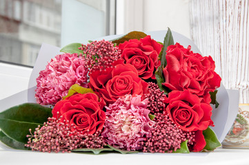 bouquet of red roses, carnations on the windowsill