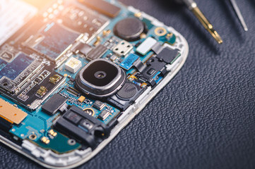 The inside of the smartphone's motherboard and tools lay on the back table. the concept of computer...