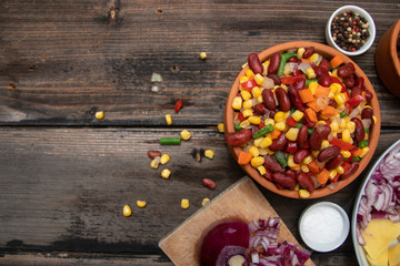 Mixture of vegetables, dried boletus mushrooms, sliced potato, red onion sliced and whole on a cutting board and spices, on old rustic wooden table. With copy space.