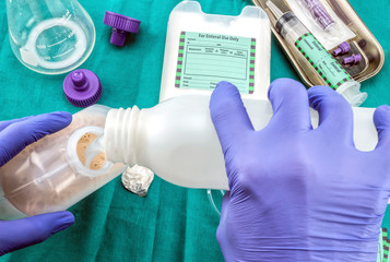 Nurse diluting with water on enteral nutrition bottle, Palliative Care, Conceptual Image,...