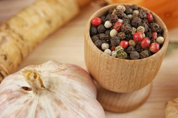 Spices on the wooden board, garlic and multi colored peppercorns