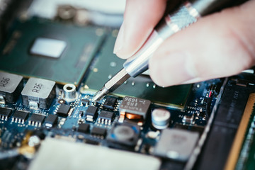 Fototapeta na wymiar Technician is fixing a computer circuit board, hand and screwdriver.