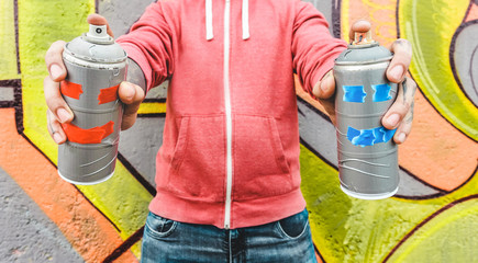 Graffiti artist painting with color spray on the wall - Focus on hands bottles