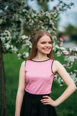 Naklejka premium Beautiful blond hair girl standing in front of the blooming tree. beautiful spring