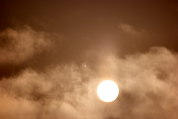 Evening background with clouds and sun. Abstract background of sun in fog. Beautiful sunrise scene in mountains.