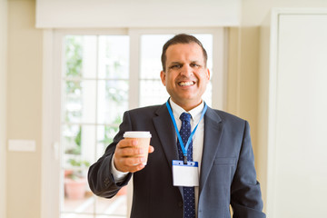 Middle age business man drinking a cup of coffee wearing identification card