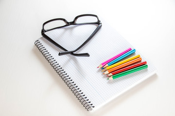 notepad glasses and pencils on the table