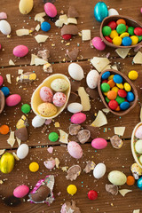 Fototapeta na wymiar easter, sweets and confectionery concept - chocolate eggs and candy drops on wooden table