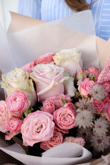 Bouquet of white and pink Roses. Woman Florist holding bouquet of Flowers indoor. Female florist preparing bouquet in flower shop. Close up. Copy space. Mother's Day and Valentine's Day concept