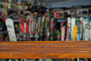 Mockup. Image of sport store with equipment for skiing. Defocused, blurred image. In the foreground is the top of a wooden table, counter.