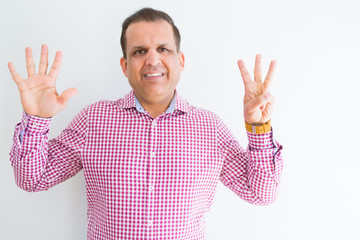 Naklejka premium Middle age man wearing business shirt over white wall showing and pointing up with fingers number eight while smiling confident and happy.