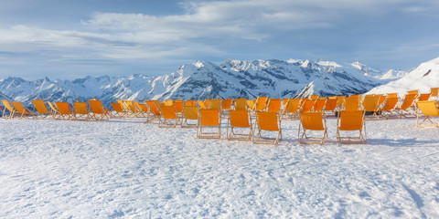 Panorama von orangenen Liegestühlen im Schigebiet in den Bergen
