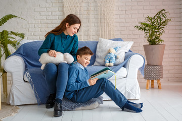 Photo session - friendly family. Brother and sister are reading a book.