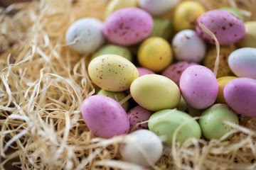 Naklejka na ściany i meble easter, confectionery and holidays concept - close up of candy drop eggs in straw nest on wooden table