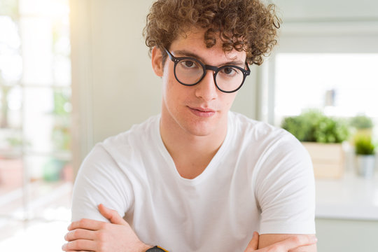 Young handsome man wearing glasses Relaxed with serious expression on face. Simple and natural with crossed arms