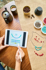 Woman making necklace according to instructions