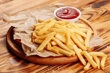 French fry Potato Snack Food Ketchup Side View. Golden Fries Meal on Wooden Rustic Board. Fresh Fast Cooked Crispy Dish of Yellow Chip Snack. Closeup Fatty Salted Dinner Portion on Paper