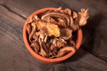 Dried wild boletus mushrooms in vintage ceramic bowl on old wooden table