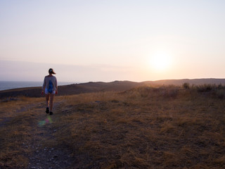 Woman walking towards the mountains at sunrise