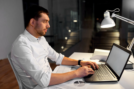 business, deadline and people concept - smiling businessman with laptop computer and papers working at night office - Powered by Adobe