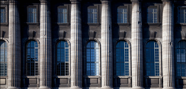 Architectural background of facede of antique building with windows and column.