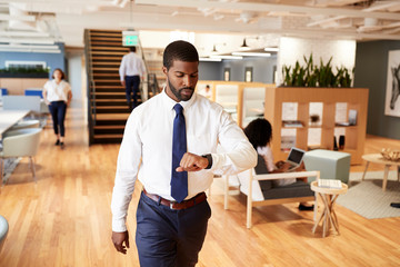Businessman Walking Through Modern Office Checking Health Data On Smart Watch