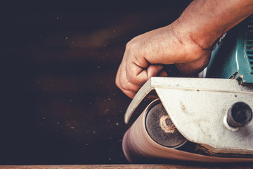 The carpenter uses power sander as a powerful tool in wood finishing.