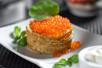 Pancakes with caviar in "Russian style" on dark background.