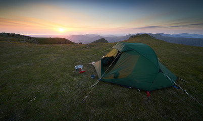 A tent pitched on the summit of Scoat Fell at sunset with views of Ennerdale in. the English Lake District.
