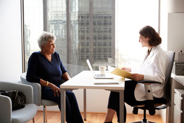 Obraz na płótnie Canvas Senior Woman Having Consultation With Female Doctor In Hospital Office