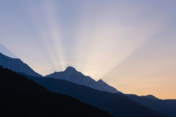 rays of rising sun behind mountain in Himalayas, India