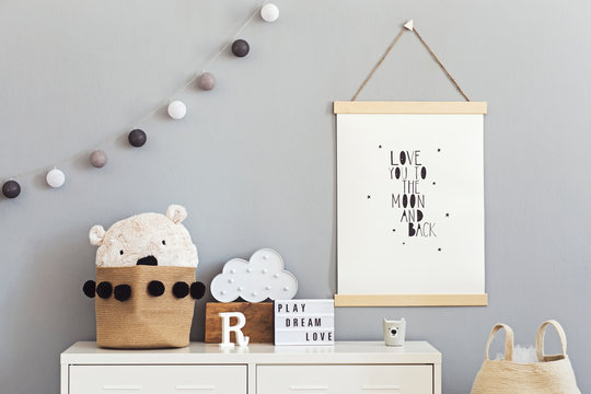 Stylish and cute scandinavian decor of  child room with mock up poster, white shelf, natural toys, hanging cotton lamps, cloud, basket for accessories and teddy bears. Bright and sunny interior.