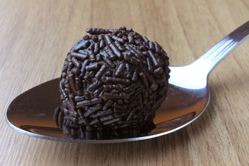 brigadeiro (brigadier), sweet chocolate typical of Brazilian cuisine covered with particles, in a wooden background.