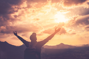 Backpacker man raise hand up on top of mountain with sunset sky and clouds abstract background.