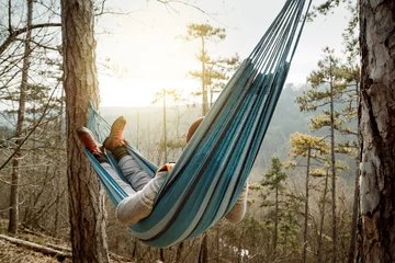 Fotobehang Young happy man relaxing lying in hammock on top of mountain. © Creaturart